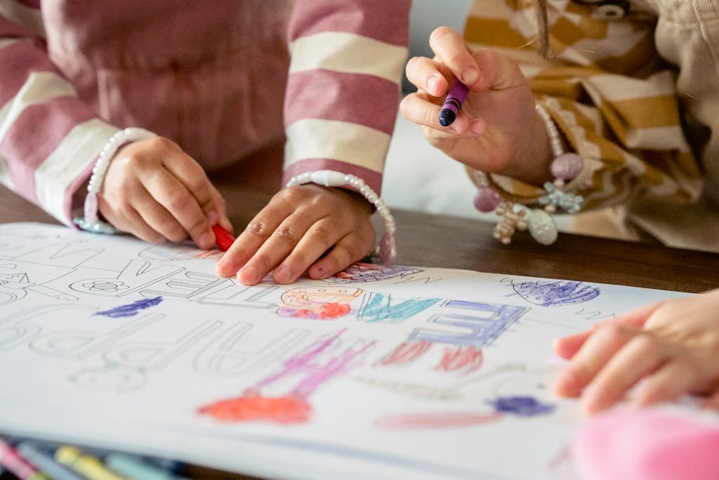 Two children collaboratively coloring a vibrant drawing with crayons indoors.